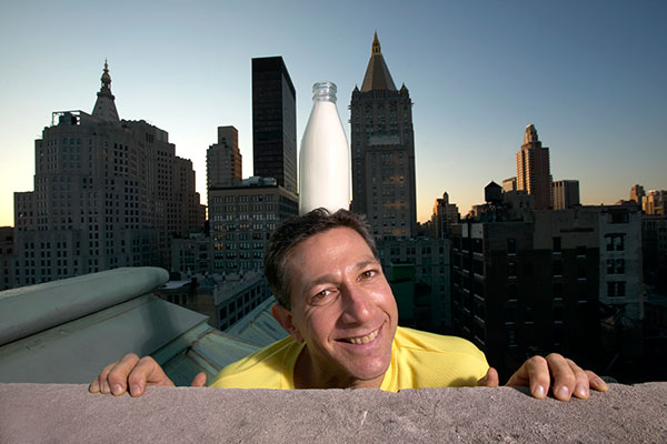 man balancing milk bottle on his head
