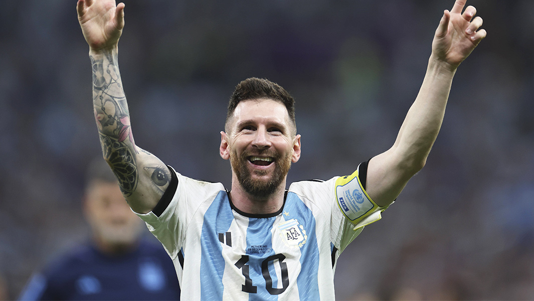 Lionel Messi raising both arms in the air and smiling