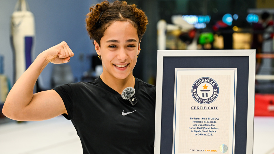 Hattan Alsaif flexing while holding her record certificate